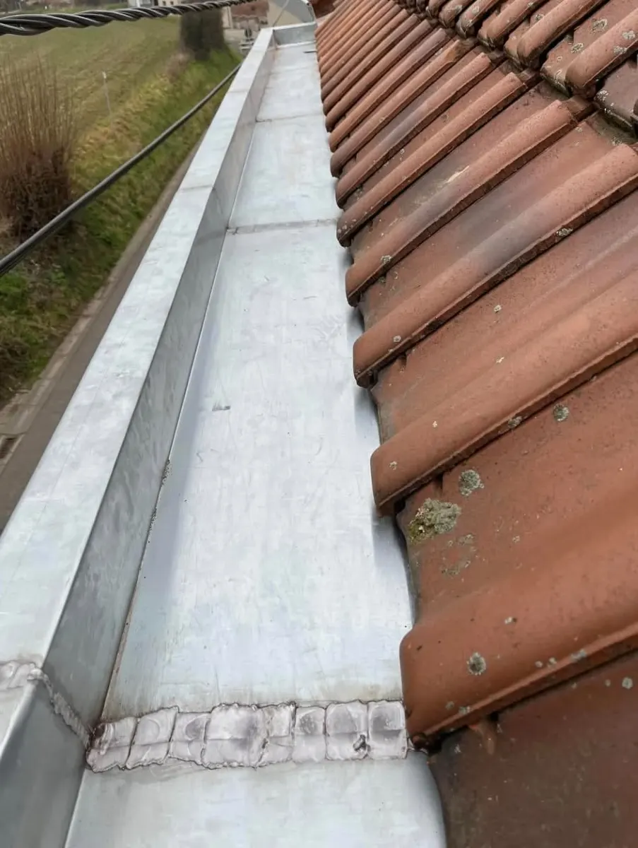 Nouveau chéneau en zinc soudé, posé le long de la toiture en tuiles par Plomberie-Toiture MERTENS B.